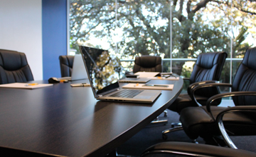 Meeting and conference room desk with arm chairs and laptops